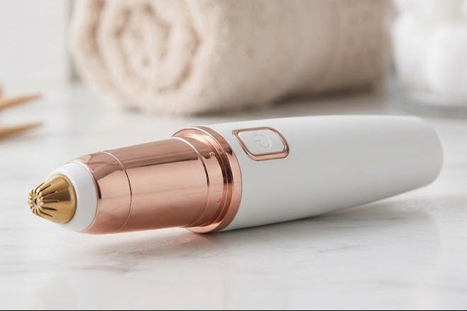 Purelia eyebrow trimmer resting on a bathroom counter beside a rolled towel